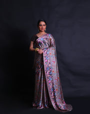 The grey satin silk saree is a vision of elegance, adorned with digital prints in satin embroidery design style that gracefully envelop the entire drape.- CRP00986