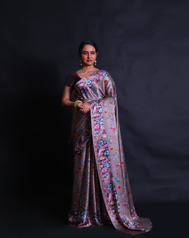 The grey satin silk saree is a vision of elegance, adorned with digital prints in satin embroidery design style that gracefully envelop the entire drape.- CRP00986