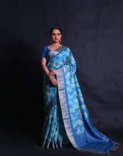 The light blue Desi Tussar saree, complemented by a zari border and pallu,- PTS05292