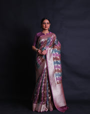 The pink Banarasi organza saree you're describing is a stunning piece, featuring multi-colored leaf designs in silver zari scattered across the drape. - BSK010622
