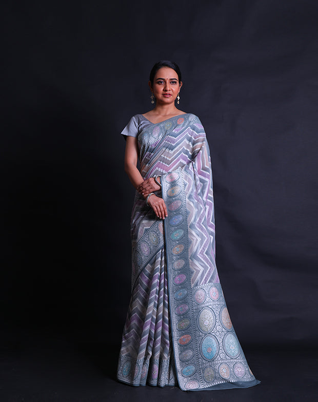 The grey semi Khadi georgette saree with light shades and zari lines in a zig-zag design,- CHG04011