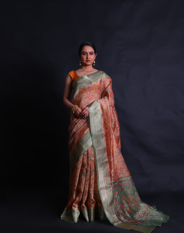 The orange semi-crusted tissue saree adorned with colorful flower designs all over the drape,- FCT011107