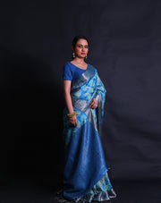 The light blue Desi Tussar saree, complemented by a zari border and pallu,- PTS05292