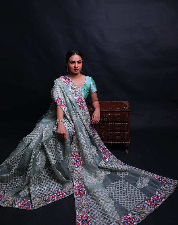 The light green organza saree you're describing is adorned with exquisite petit point embroidery in a modern design along the border,- EMB03360