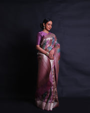 The pink Banarasi organza saree you're describing is a stunning piece, featuring multi-colored leaf designs in silver zari scattered across the drape. - BSK010622