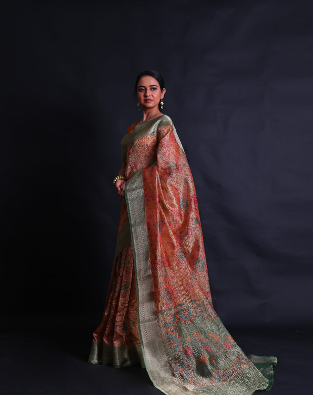 The orange semi-crusted tissue saree adorned with colorful flower designs all over the drape,- FCT011107