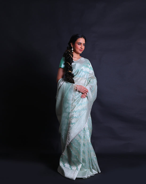 The light green pure kora saree radiates elegance with its intricate silver zari and thread work adorning the entirety of the drape,- BSK010527