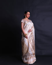 The beige tela zari Kota saree adorned with gold zari buttis all over the drape exudes classic elegance and sophistication.- KTJ04071