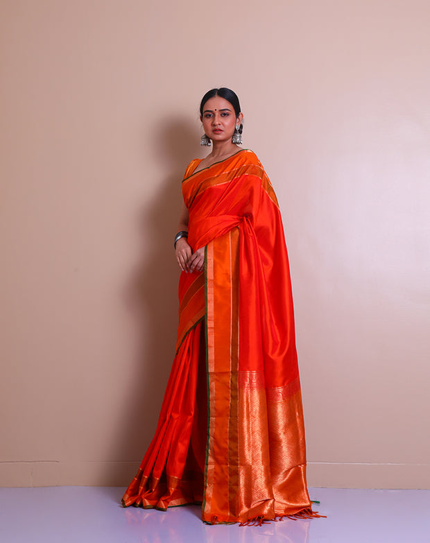 An orange Kanjivaram soft silk saree features elegant self-lines woven throughout the drape, - KSL03001