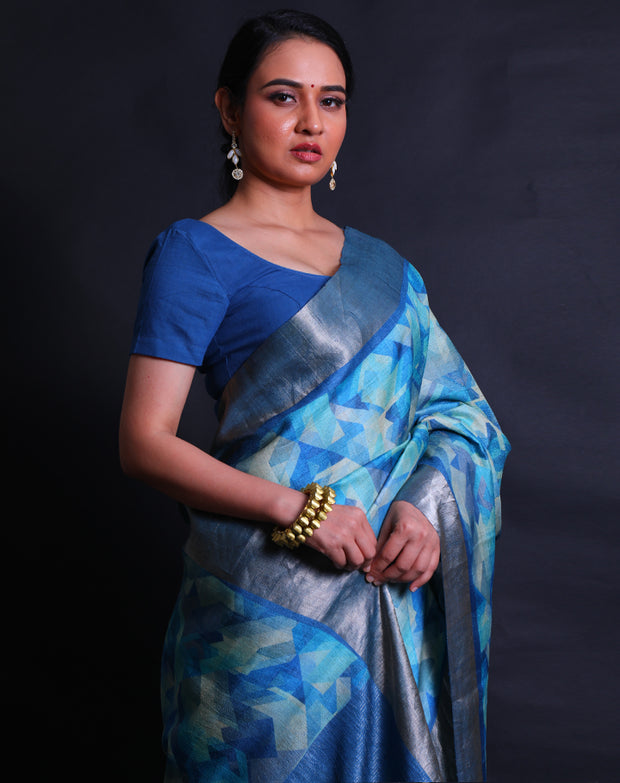 The light blue Desi Tussar saree, complemented by a zari border and pallu,- PTS05292