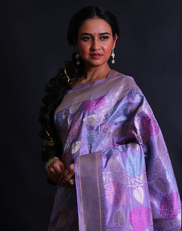 The light mauve Banarsi silk saree exudes elegance with its intricate leafy design woven delicately in zari and thread,- BSK010512