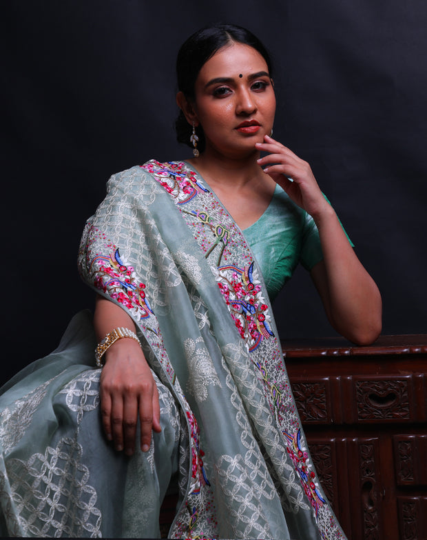 The light green organza saree you're describing is adorned with exquisite petit point embroidery in a modern design along the border,- EMB03360
